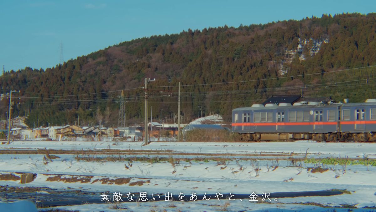 雪の田んぼの向こうを走る電車