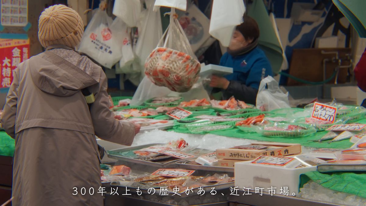 鮮魚店の店先で買い物をする人