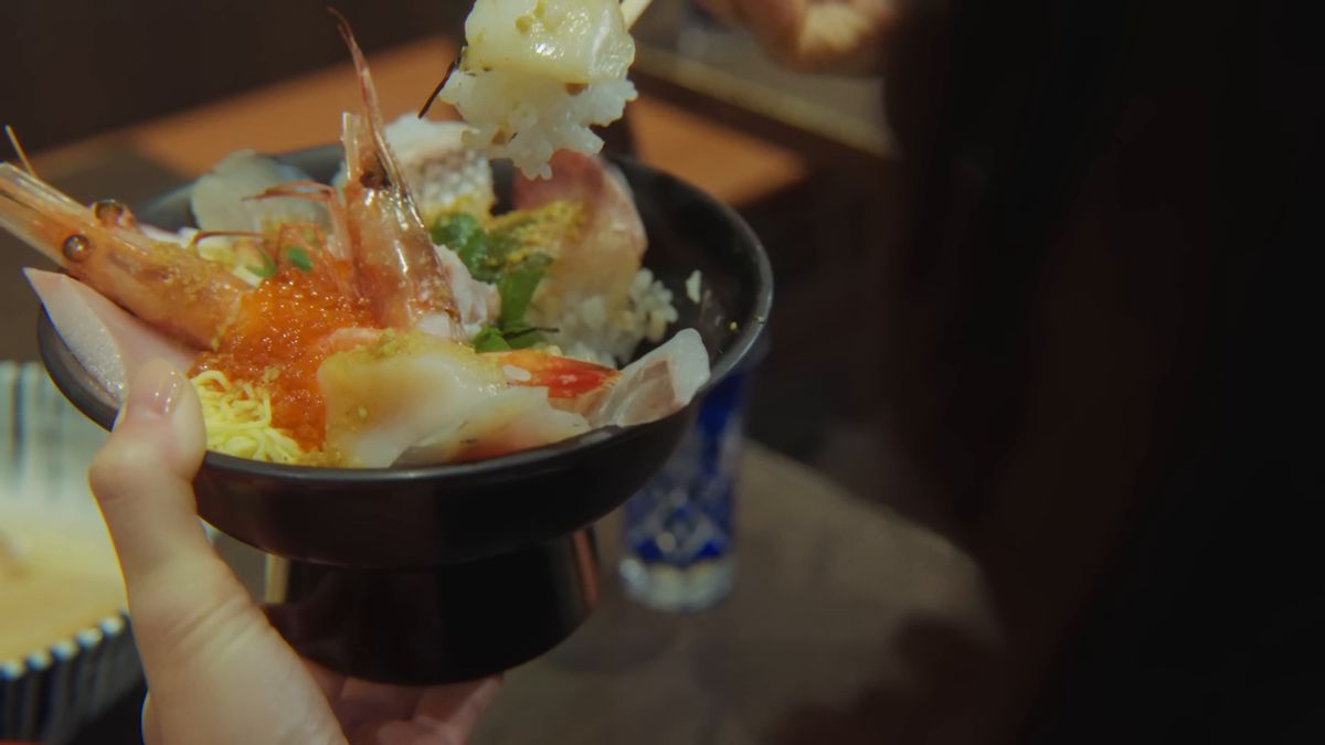 海鮮丼を手に、ご飯をすくう