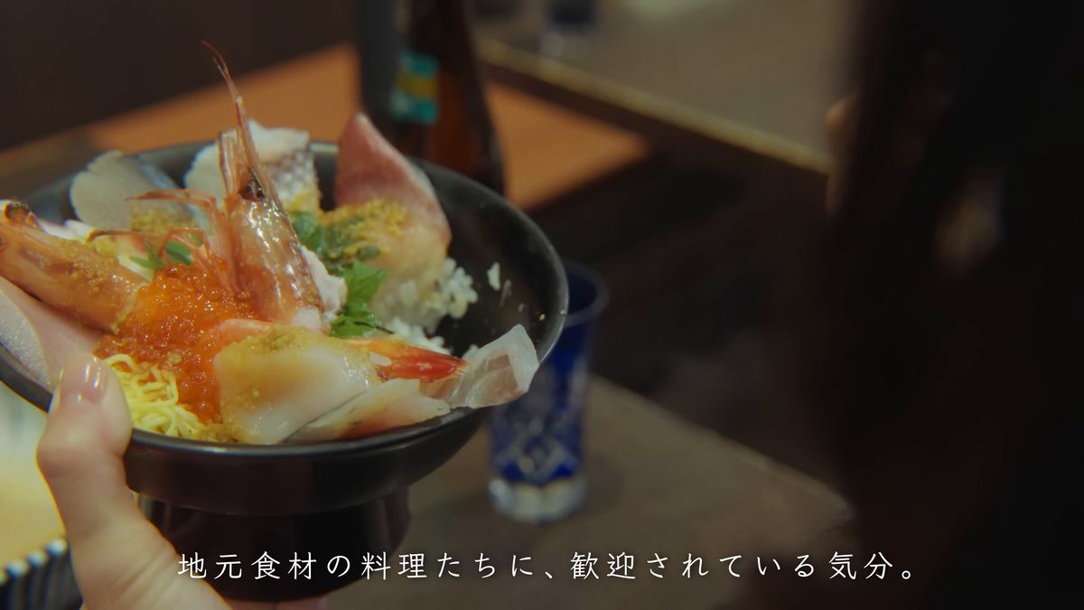 甘えびといくらがのった丼を持ち上げる