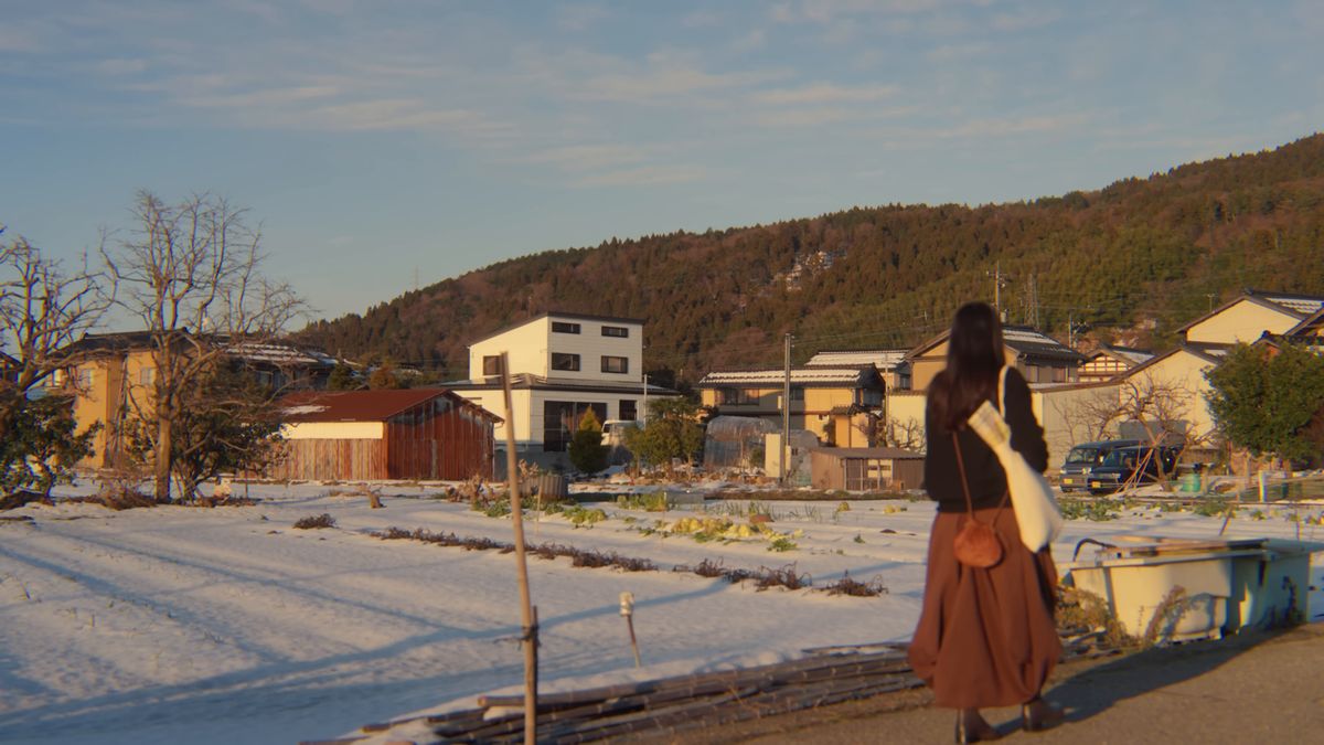 雪の畑沿いの道を歩く後ろ姿