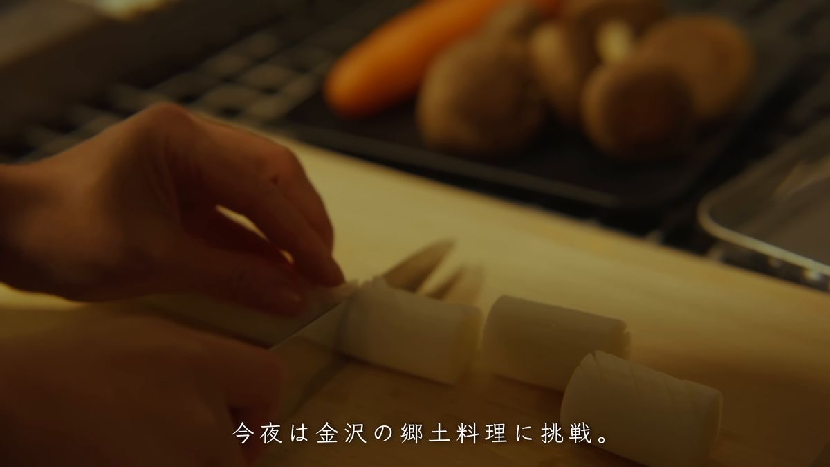 にんじんやしいたけを前に、ねぎを切る