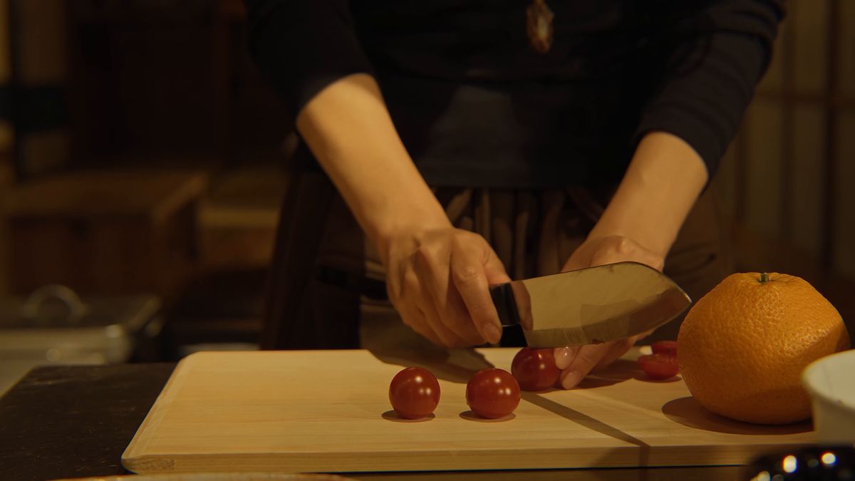 まな板の上でミニトマトを切る手元と柑橘