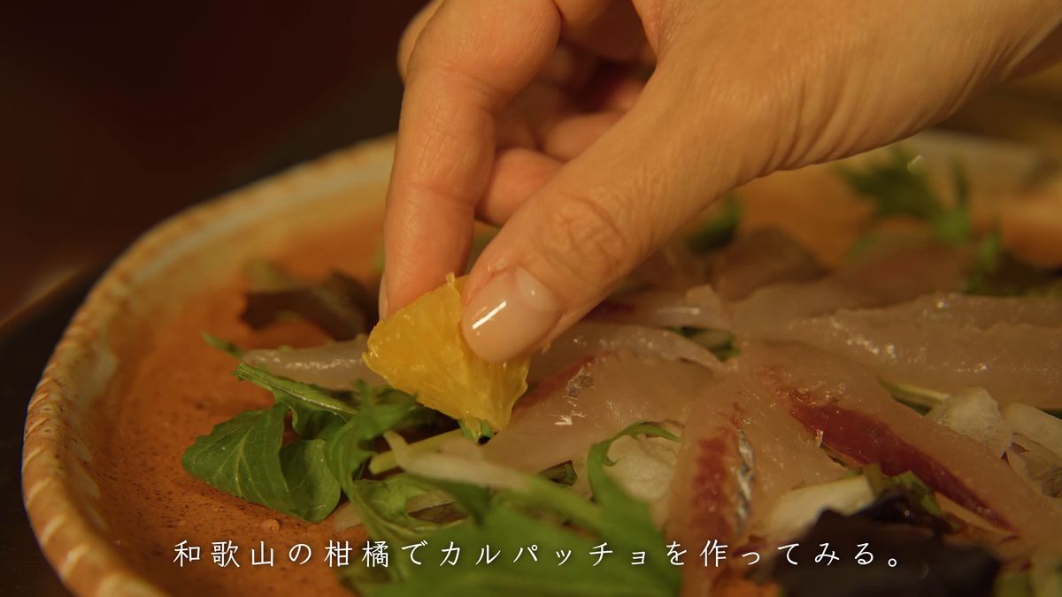 トビウオの刺身と葉野菜の上に柑橘の果肉をのせる
