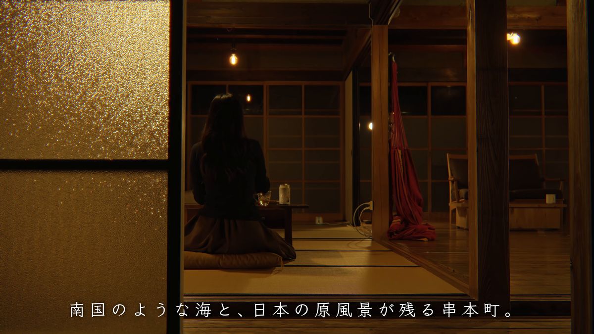 夜の板の間に座り、庭を眺める後ろ姿