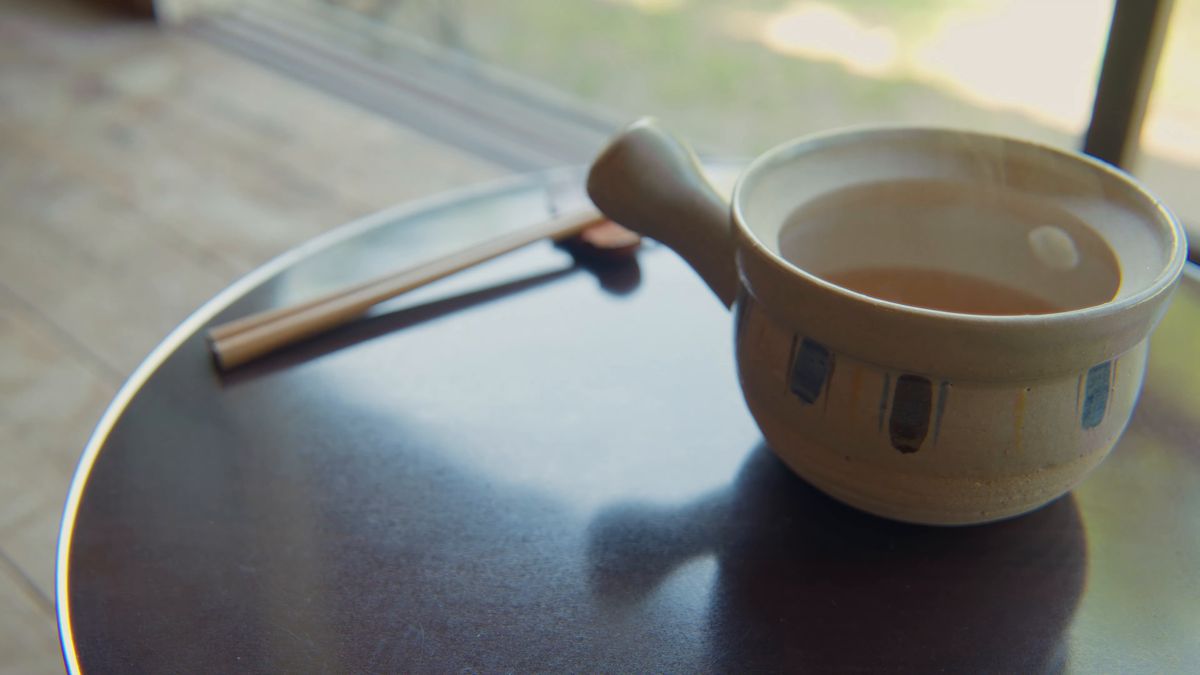 丸い卓の上のだし汁の土瓶と箸