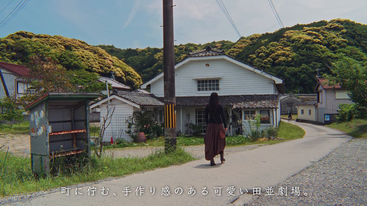 白い板壁の田並劇場へ歩く後ろ姿