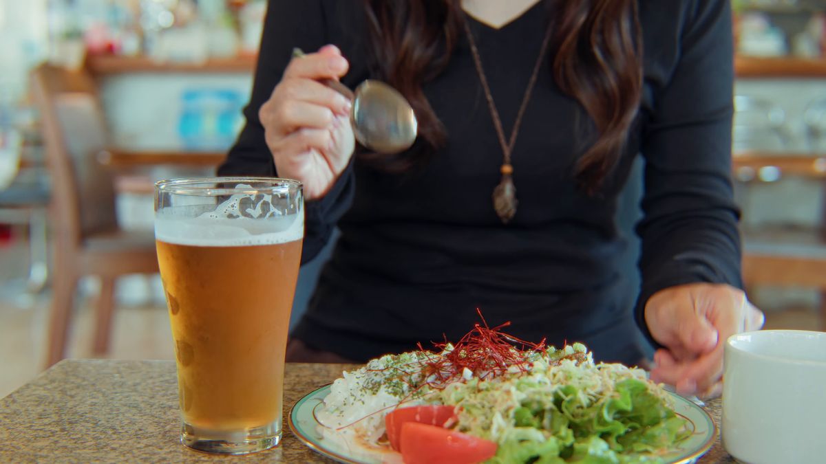 ケバブライスの皿とビールのグラスを前にした手元