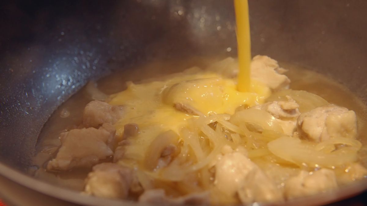 鶏肉と玉ねぎの鍋に溶き卵を回し入れる