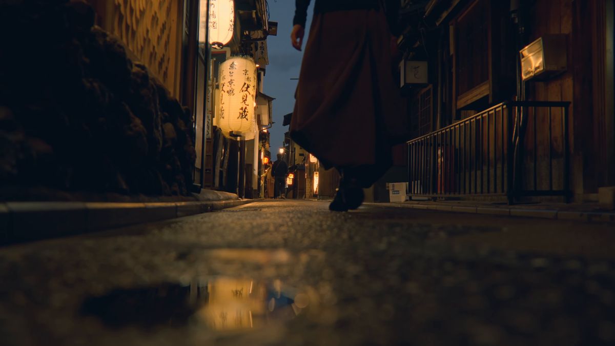 提灯の灯りが映る夜の路地を歩く足元