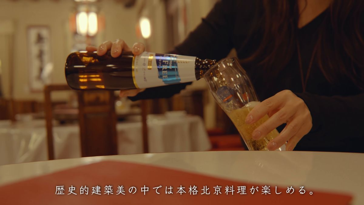 白いクロスの卓で瓶ビールをグラスに注ぐ