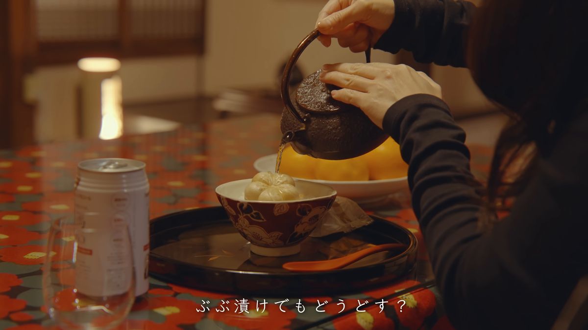 赤い花柄の卓で、鉄瓶の湯を茶碗に注ぐ