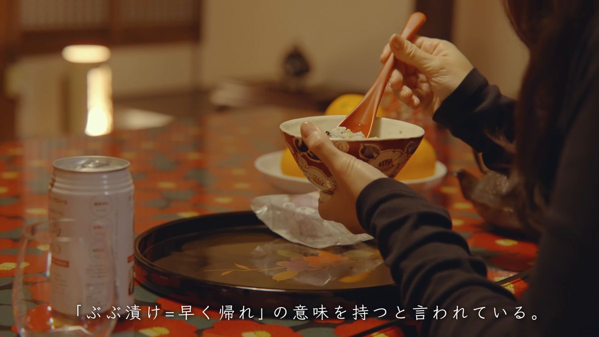 赤い花柄の卓で、茶碗を手にぶぶ漬けを食べる