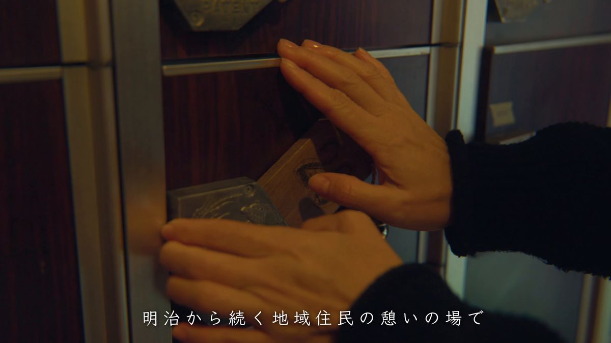 下足箱の扉に木札の鍵を差す手元
