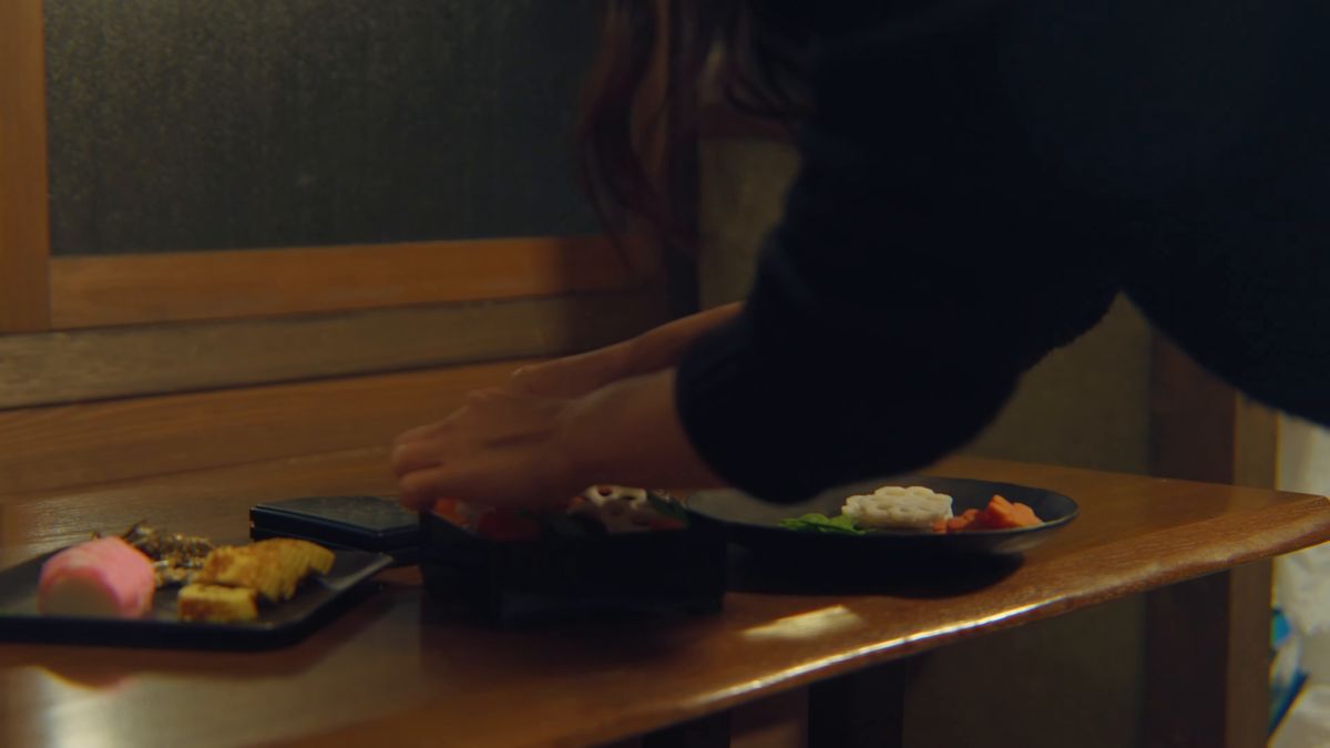 台所の卓で、重箱に料理を詰める