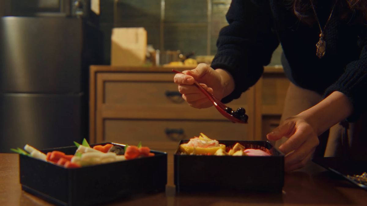 二段の重箱に、赤い匙で黒豆を盛る