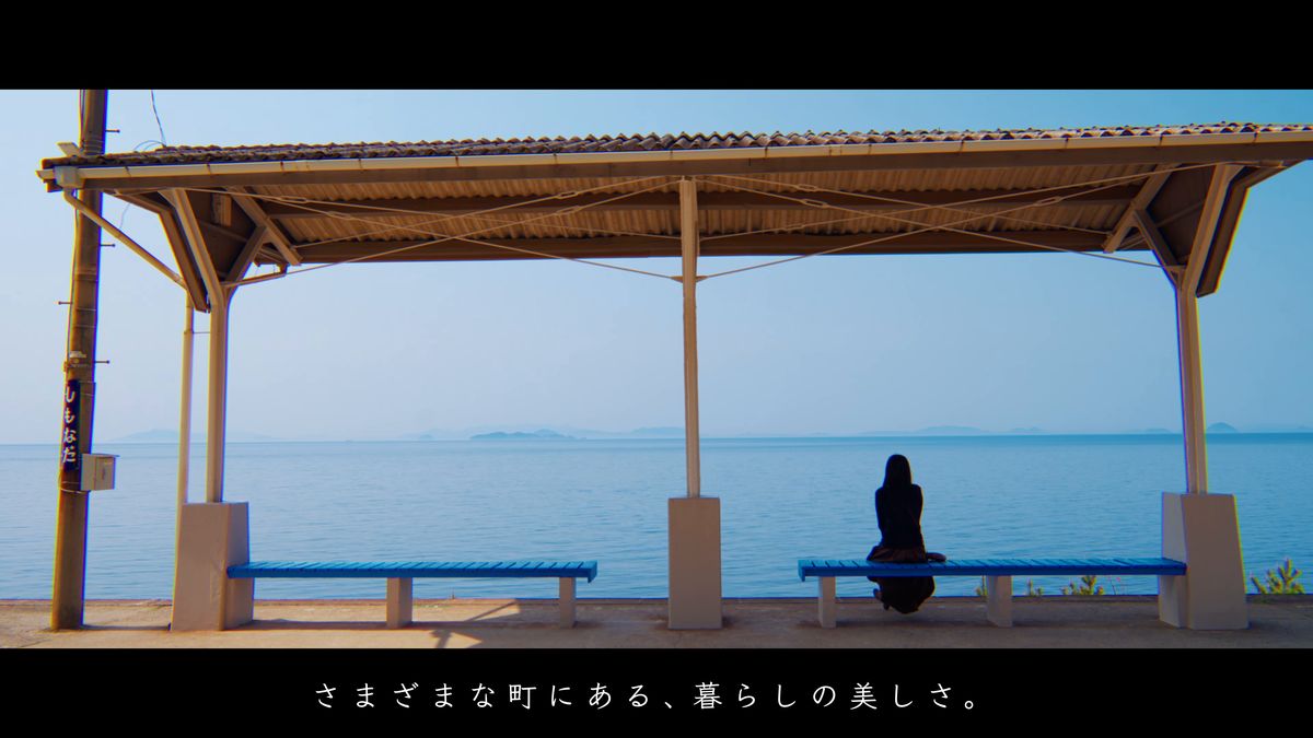 海に面した駅のベンチに座る後ろ姿