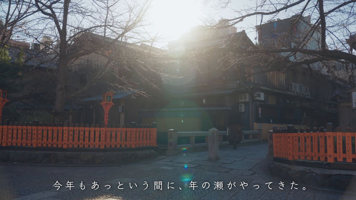 朝日を受ける朱塗りの玉垣と町家