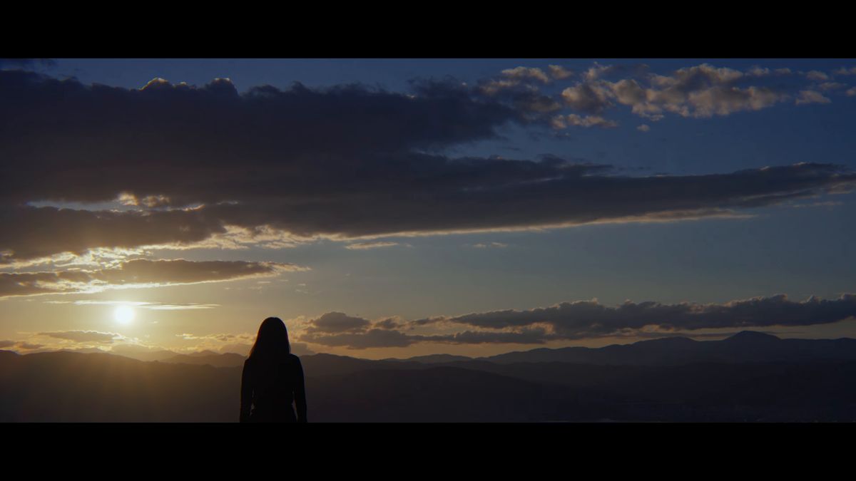 山並みに沈む夕日と人影