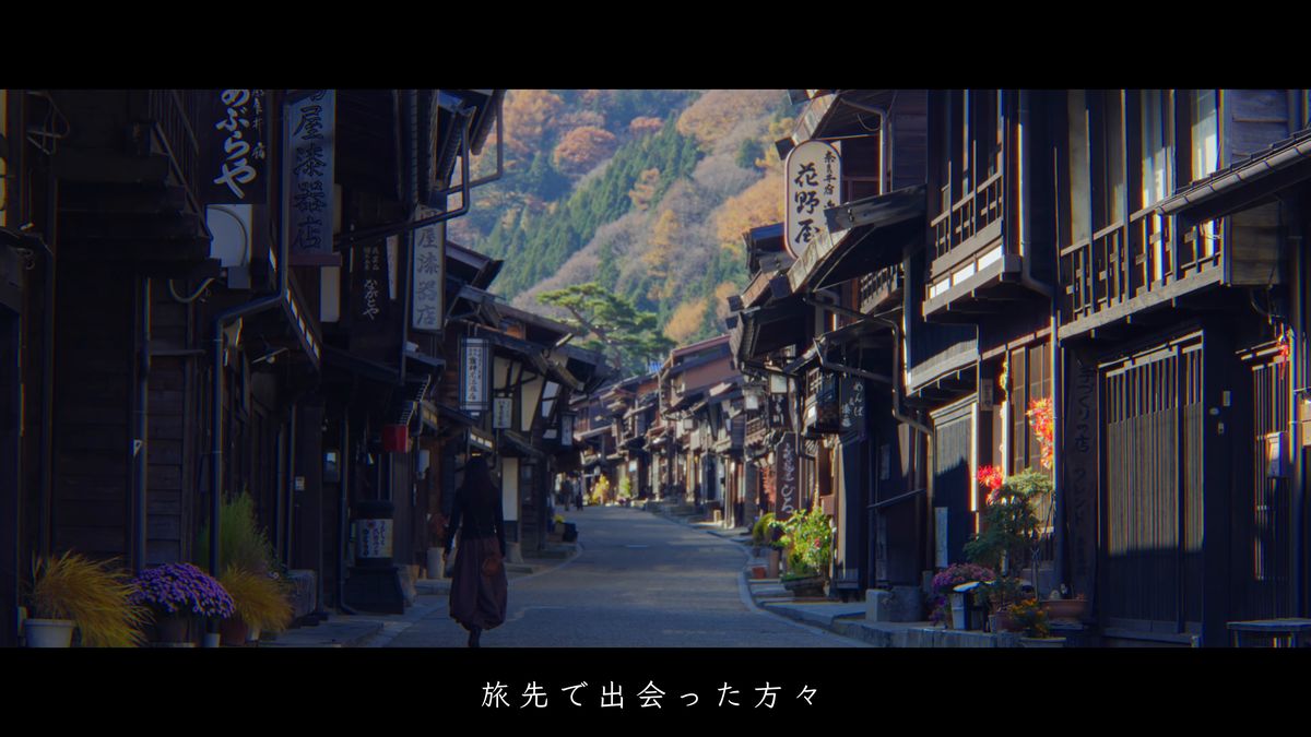 紅葉の山を背にした宿場町を歩く後ろ姿