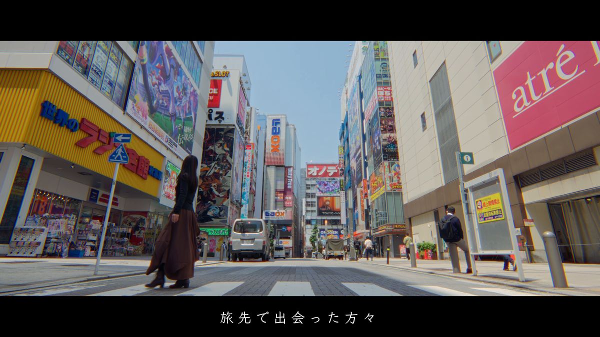 ビルが並ぶ繁華街の横断歩道を渡る後ろ姿