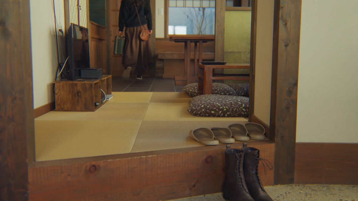 畳の間の奥へ歩いていく後ろ姿と、土間の靴