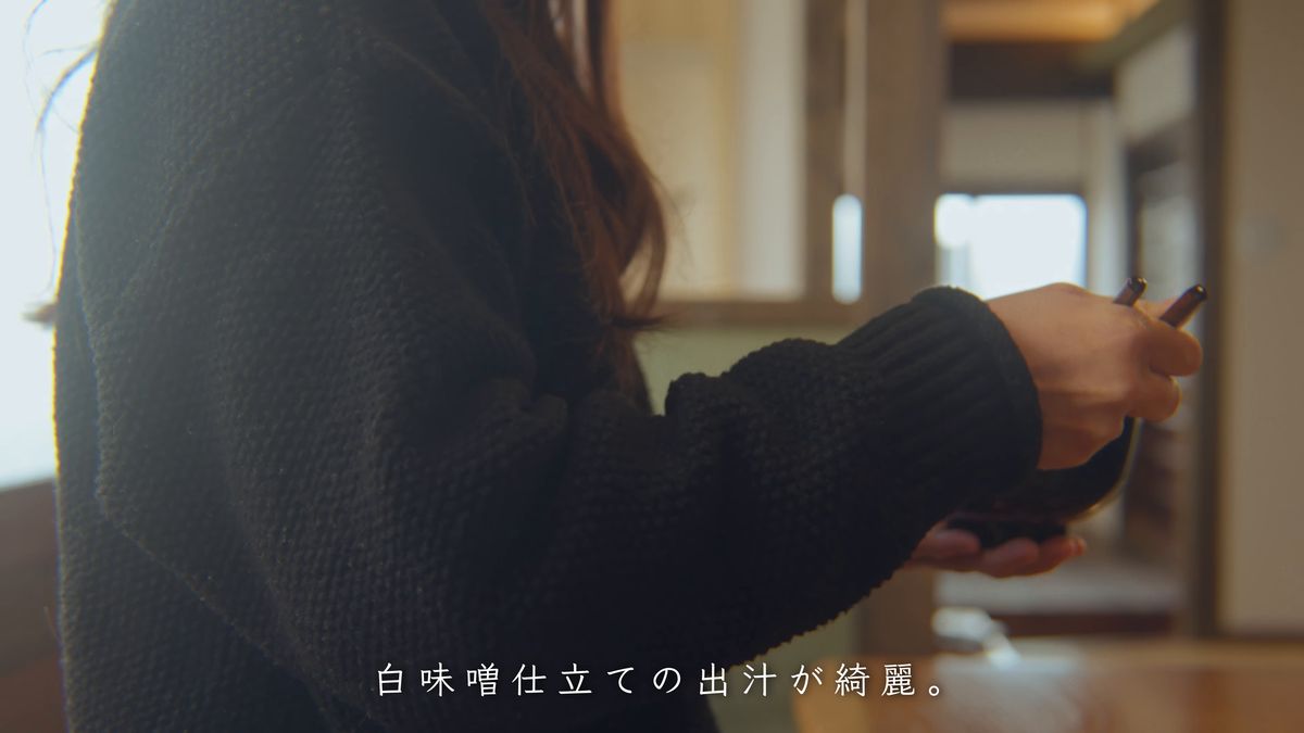 椀と箸を手に、窓辺に立つ後ろ姿