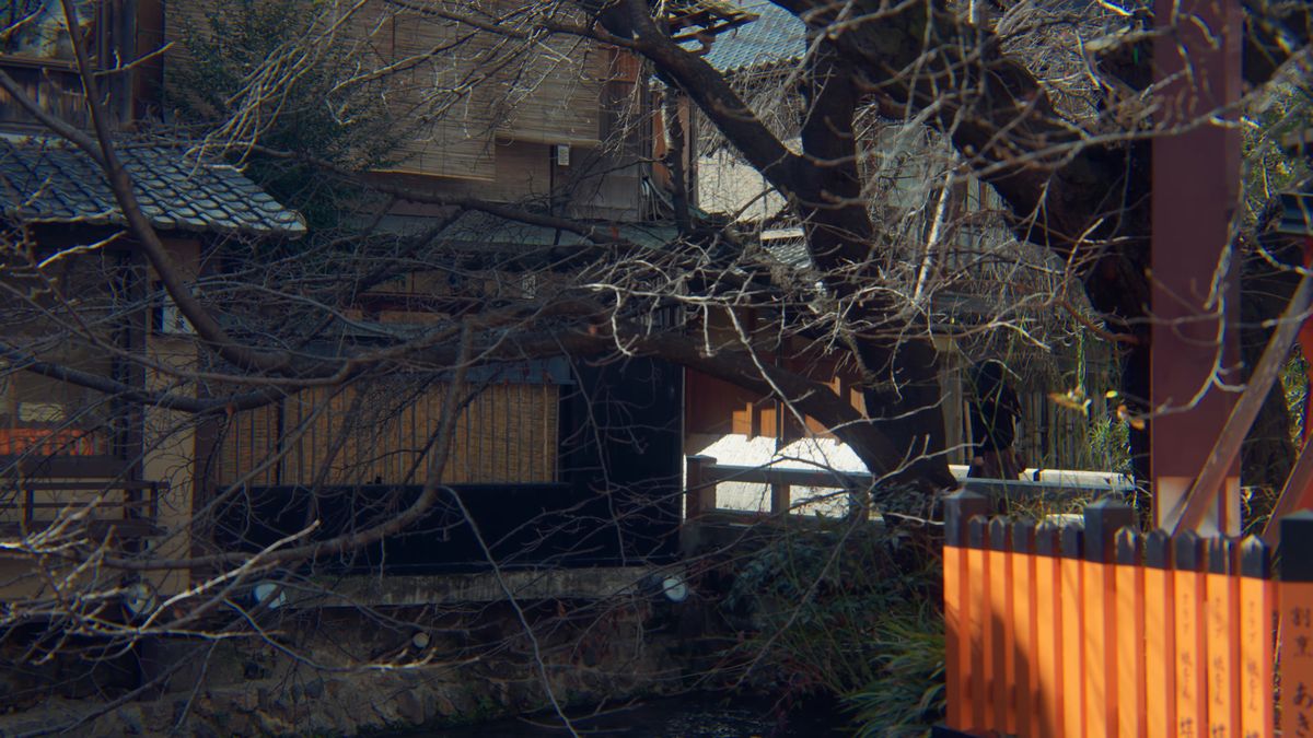 朱の玉垣のそばに建つ町家