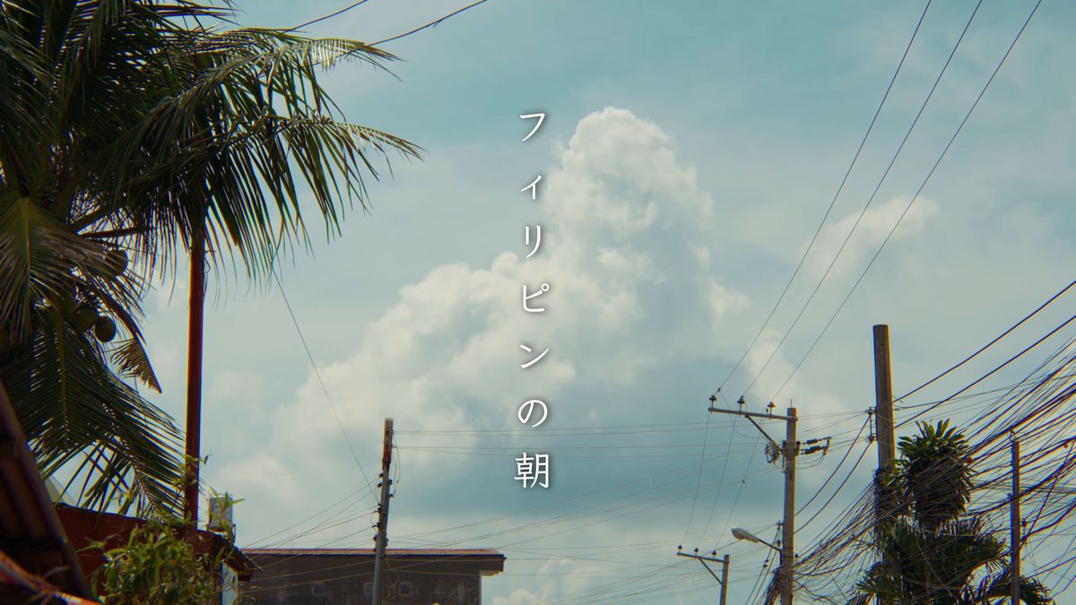青空に湧く入道雲と、ヤシの葉と電線