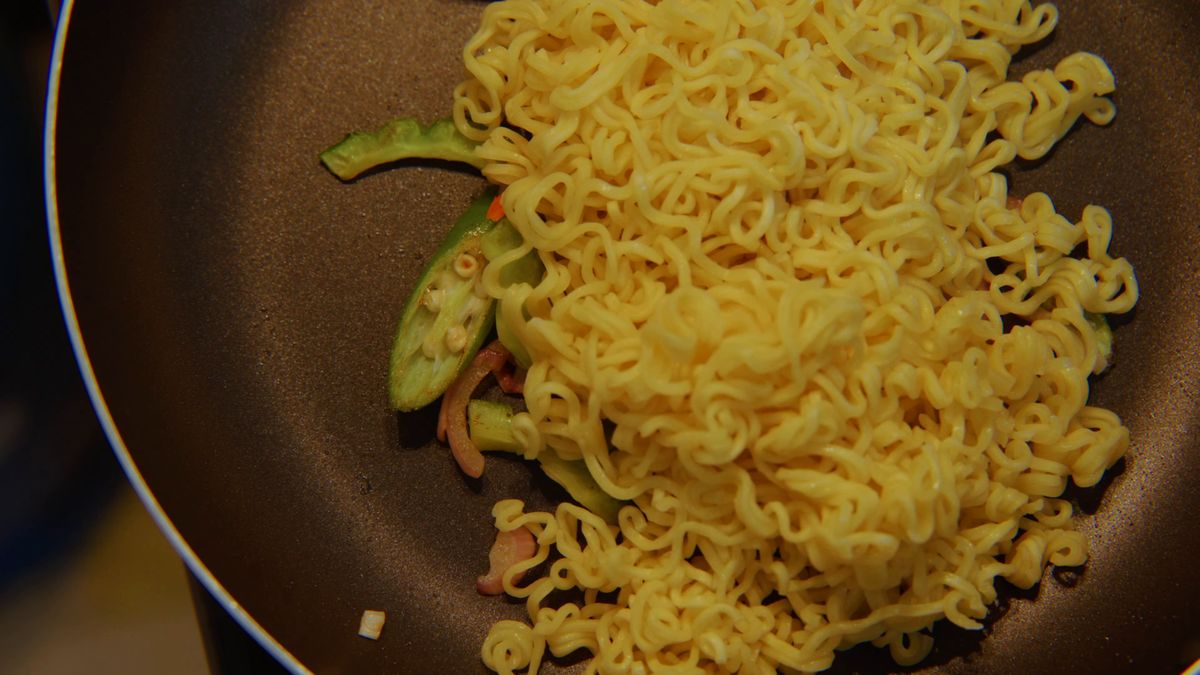 野菜を炒めたフライパンに入れた麺