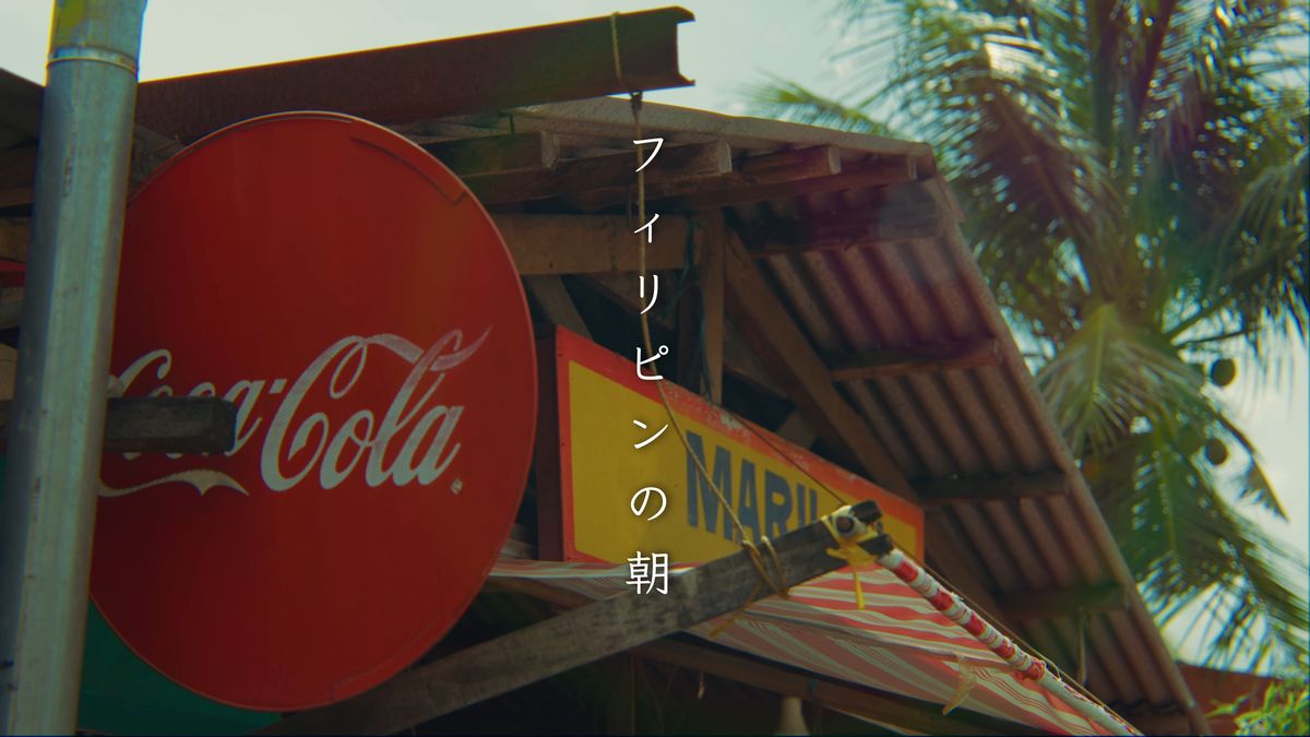 トタン屋根の店に掲げたコカ・コーラの丸い看板