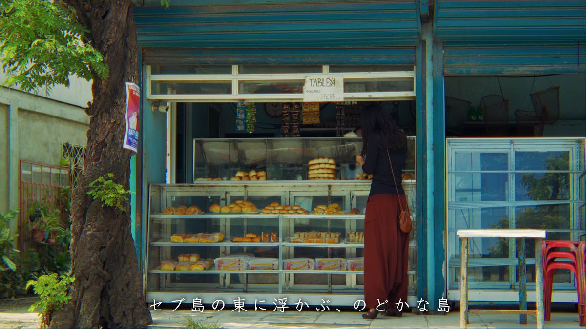 青い壁のパン屋の店先に立つ後ろ姿