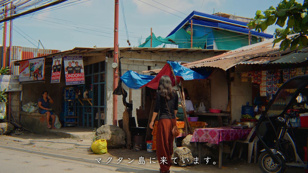ポスターが貼られた店先を歩く後ろ姿