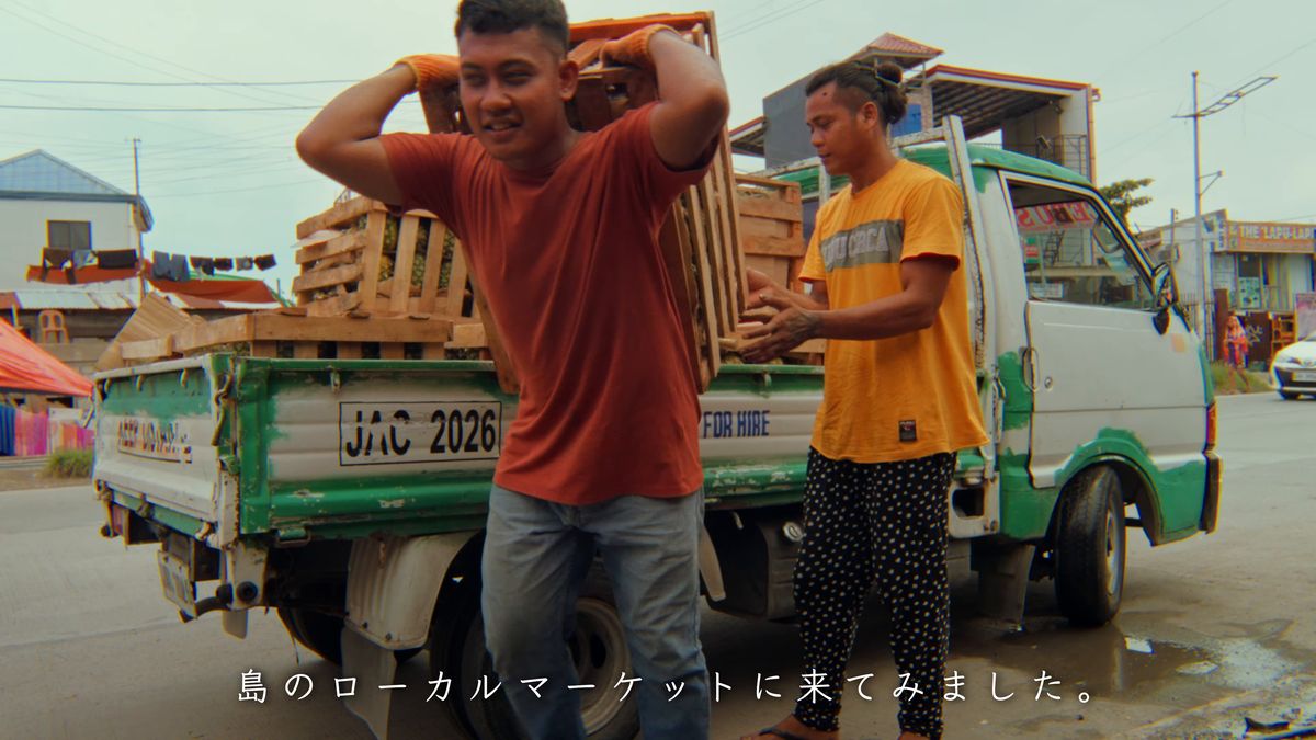 トラックの荷台から木箱を降ろす人たち