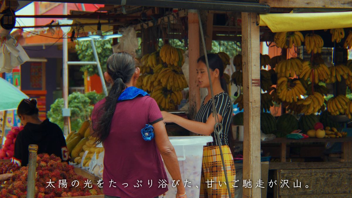 バナナとランブータンが並ぶ屋台の前の人々