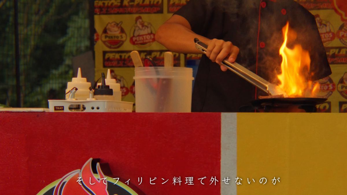 屋台の厨房で炎を上げるフライパン