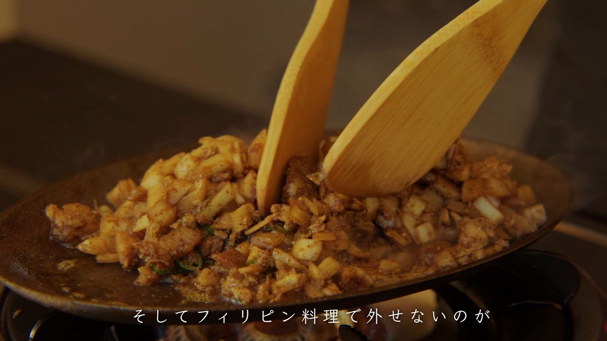 鉄板の上で木べらで炒めるシシグ