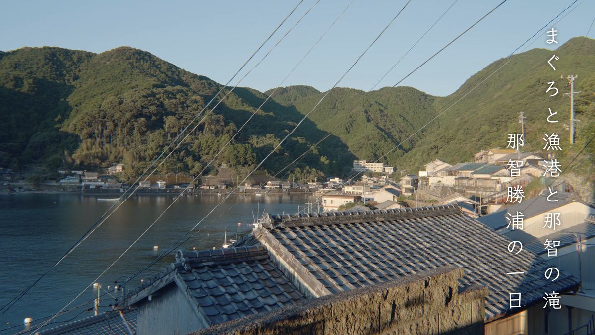 湾の奥に家々が並ぶ漁村と、手前の瓦屋根