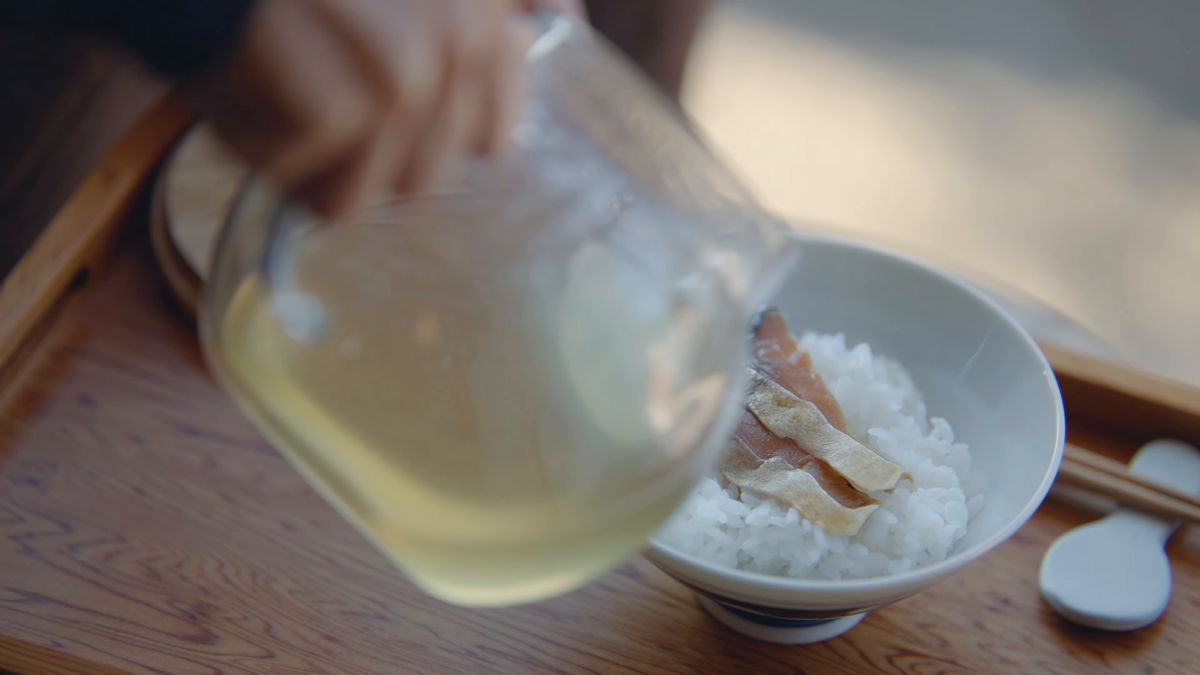 ガラスの急須から、へしこをのせたご飯に茶を注ぐ