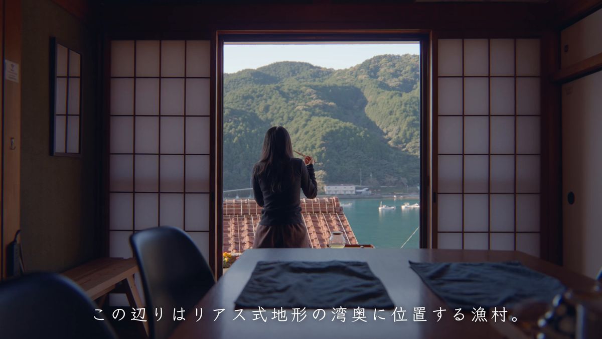 障子の間から、窓辺で湾を眺める後ろ姿