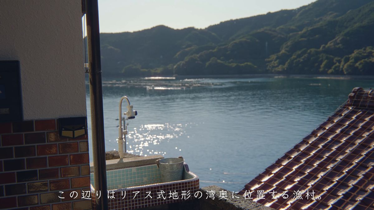 流しの蛇口と、瓦屋根の向こうに光る湾