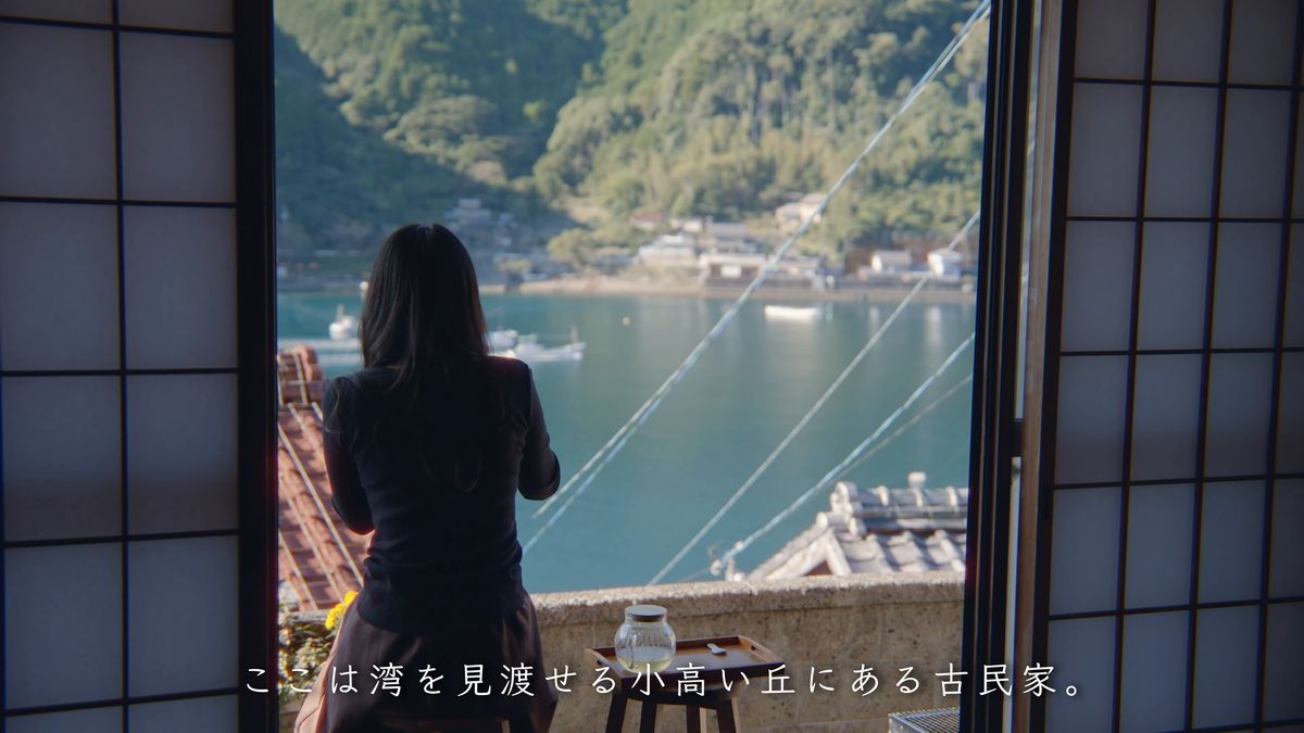 障子を開け放った窓辺から海を眺める後ろ姿