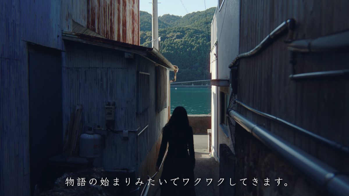 板壁の路地の先に見える海へ向かう後ろ姿