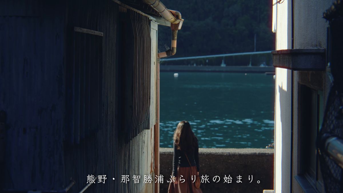 トタンの家並みの間からのぞく湾と後ろ姿