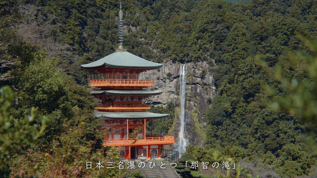 山を背に立つ朱色の三重塔と、一筋に落ちる那智の滝