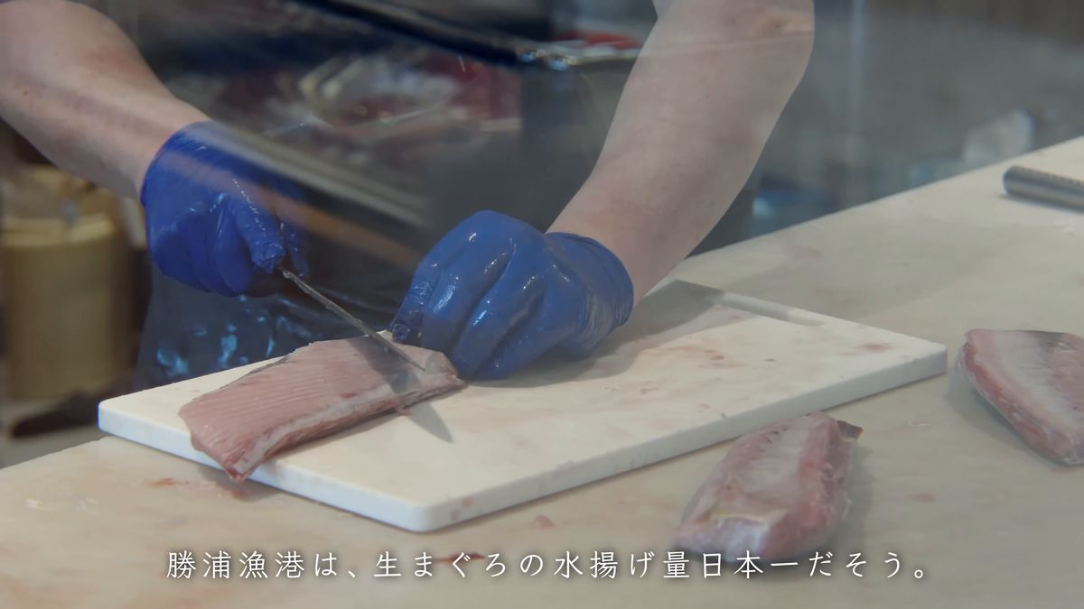 青い手袋でまぐろの柵を切り分ける手元