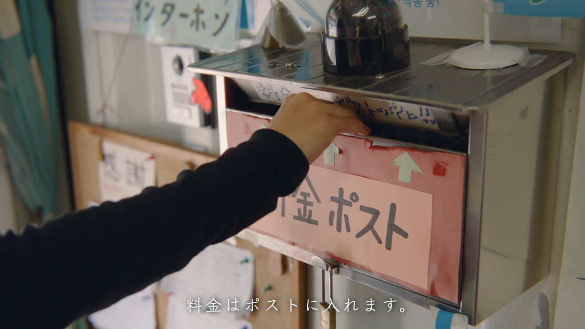 料金ポストにお金を入れる手元