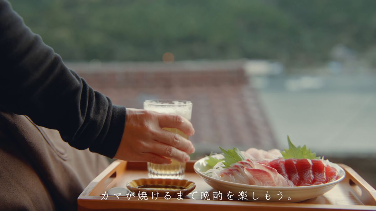グラスを手に取る手元と刺身の皿