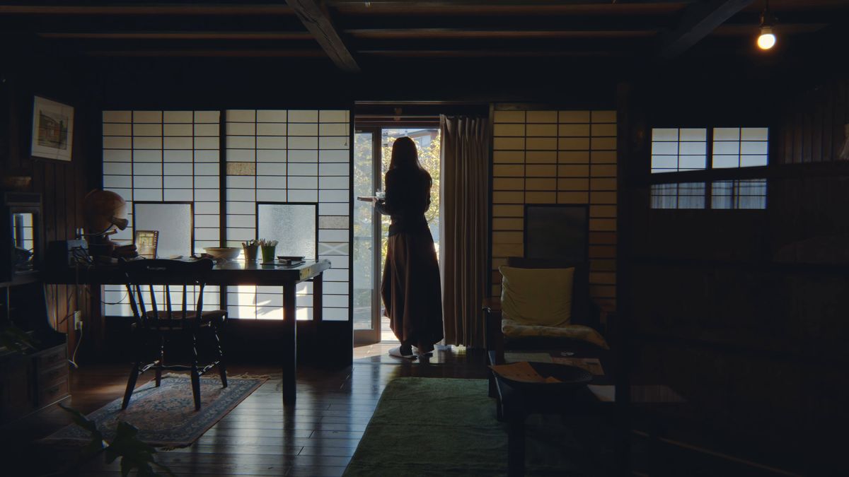 障子の間の奥、開いた戸口に立つ後ろ姿