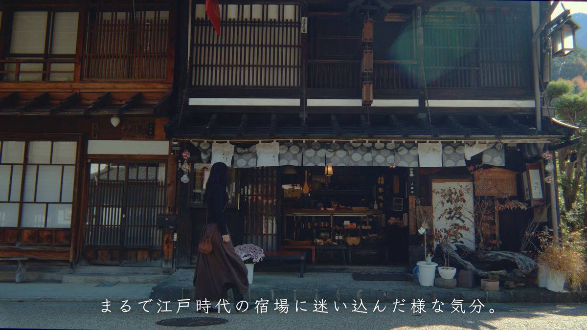 二階建ての町家の前を歩く後ろ姿